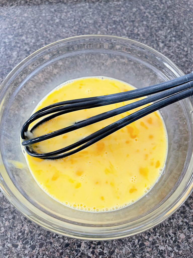 Beaten eggs and milk in a mixing bowl.