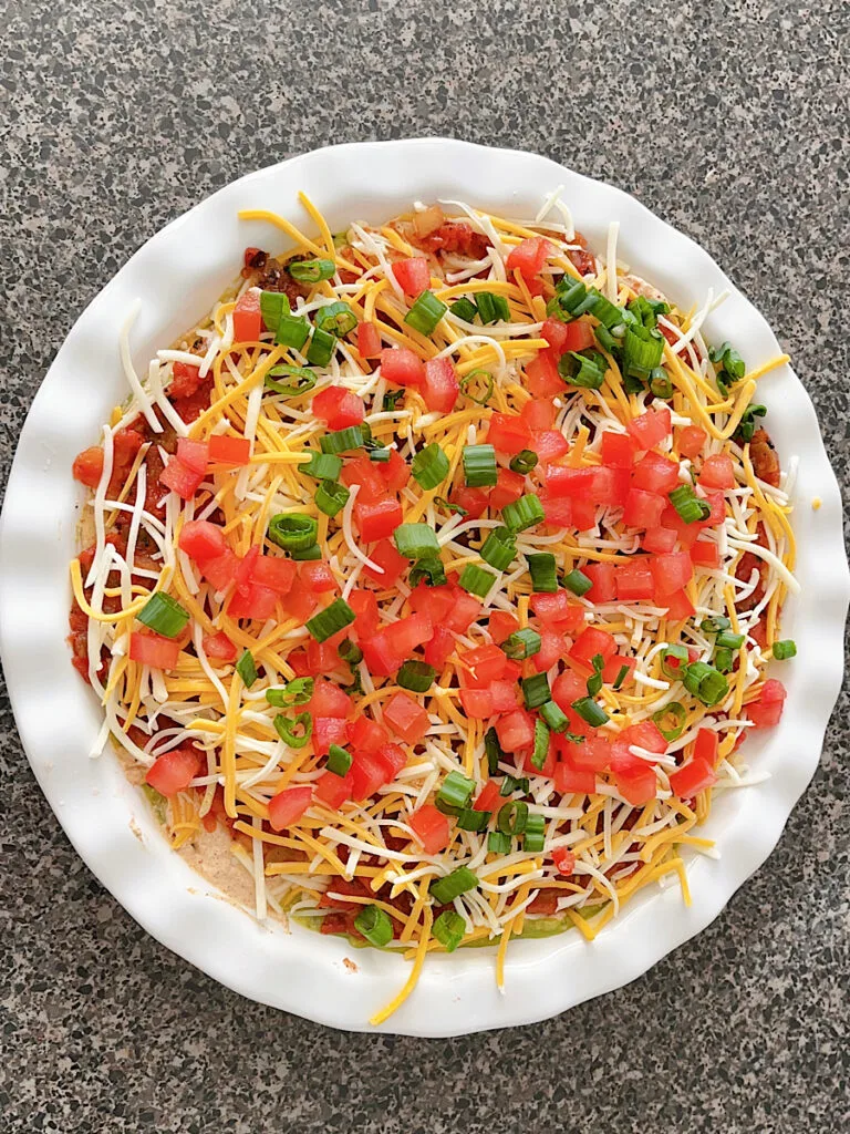 Green onions sprinkled over seven layer dip.