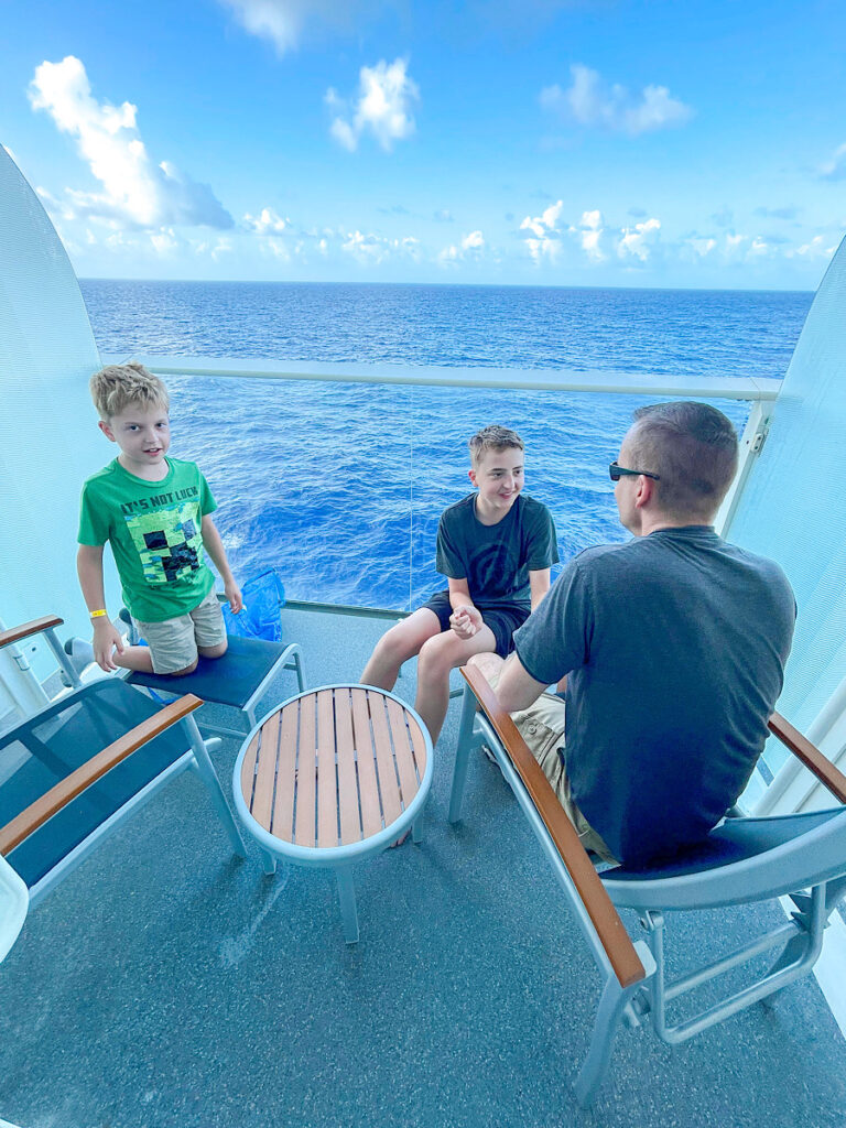 A dad and two kids on the balcony of Harmony of the Seas stateroom 7666.