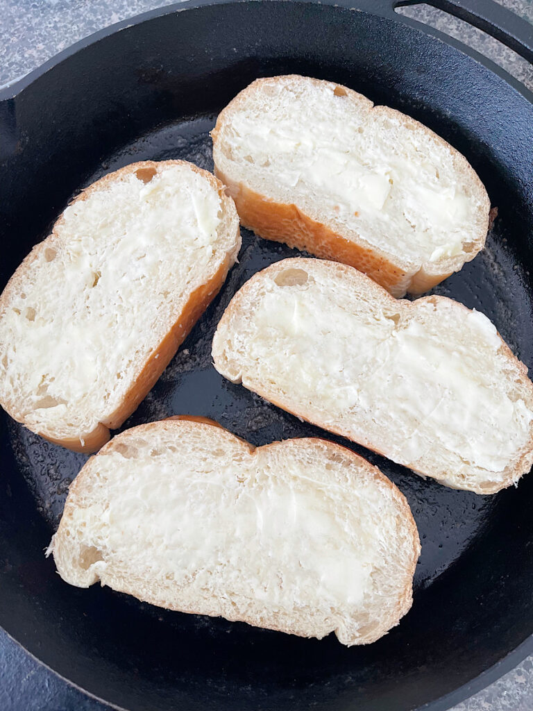 Bread toasting in a cast iron skillet.