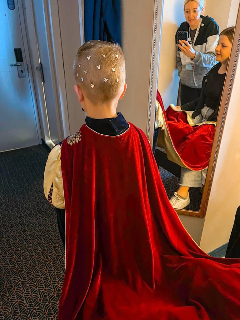 A boy dressed in a Knight costume looking in the mirror in the Bibbidi Bobbidi Boutique.
