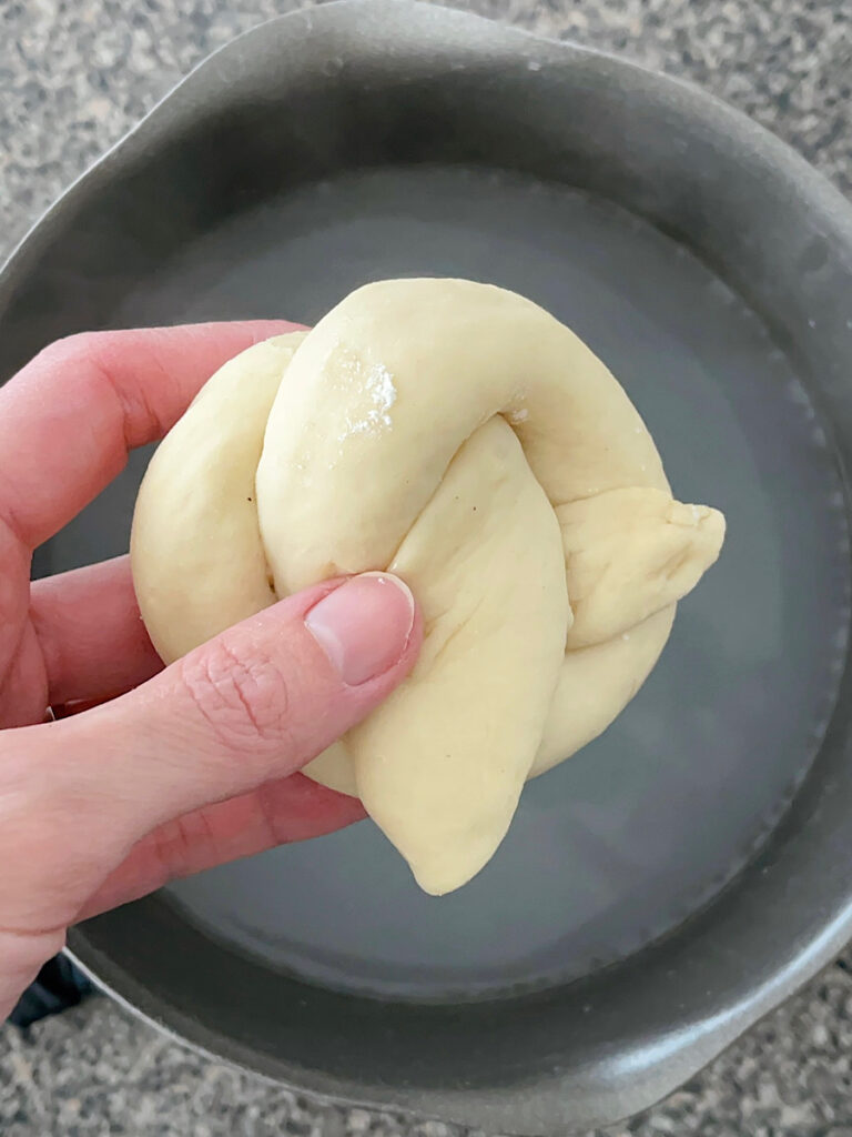 A soft pretzel about to go into a baking soda bath.