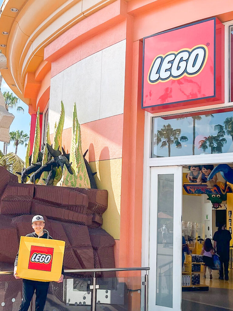 A teenager holding a LEGO bag outside the LEGO Store at Downtown Disney.