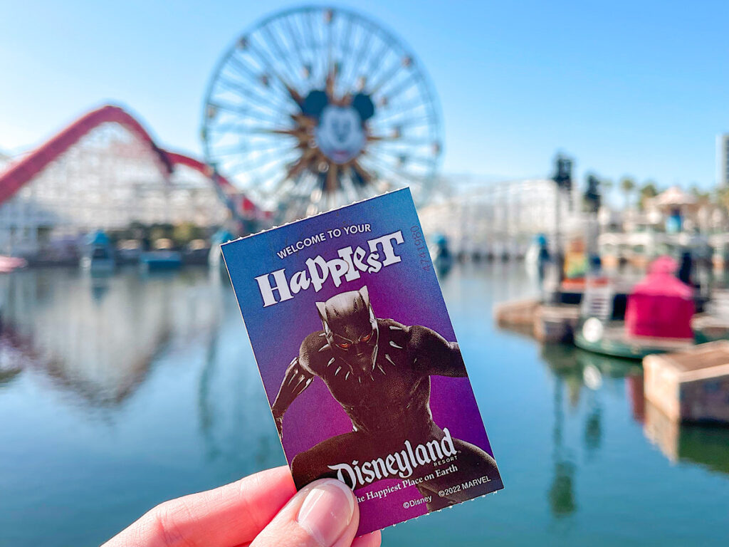 A Disneyland Park Hopper Ticket in front of a Mickey ferris wheel.