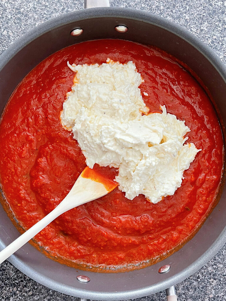 A ricotta and mozzarella cheese mixture in a pan with marinara sauce.