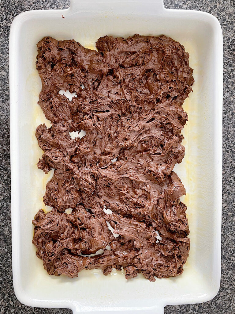 Brownie batter spread in a 9x13 baking dish.