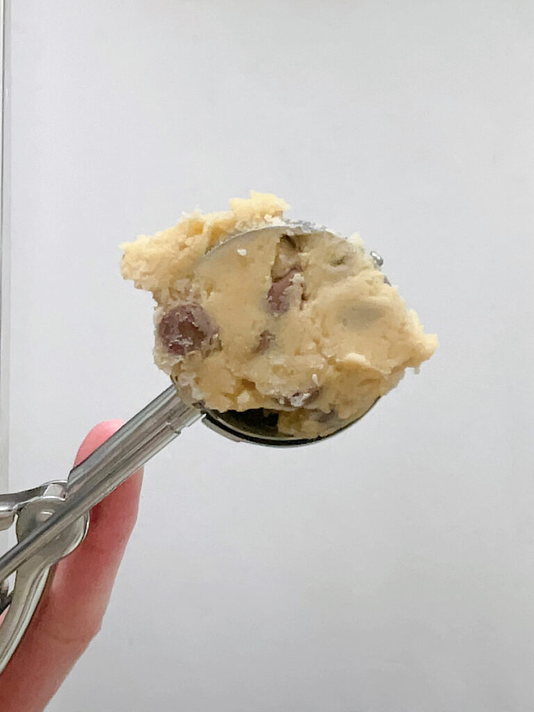A cookie scoop full of chocolate chip cookie dough.