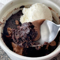 A chocolate mug cake made without eggs and topped with Nutella and vanilla ice cream.