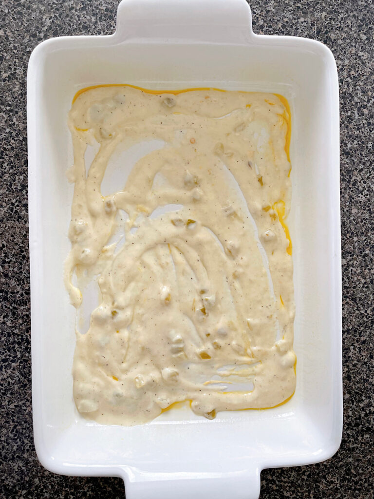 Sour cream enchilada sauce on the bottom of a baking dish.