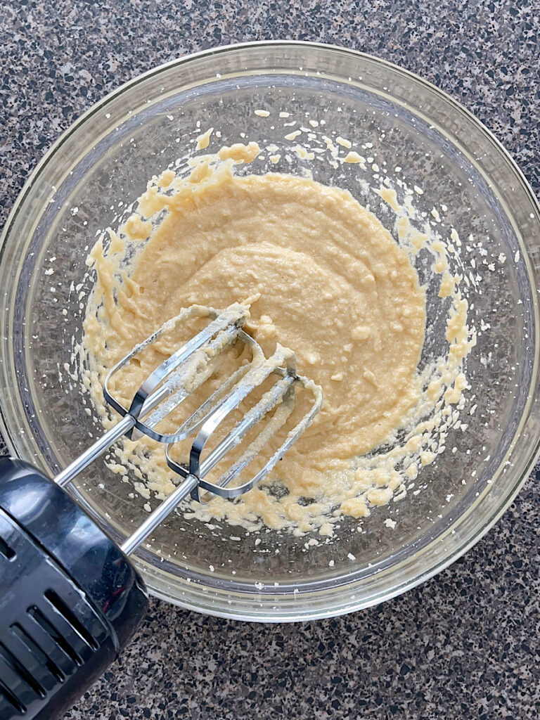 Cookie dough in a mixing bowl with an electric mixer.