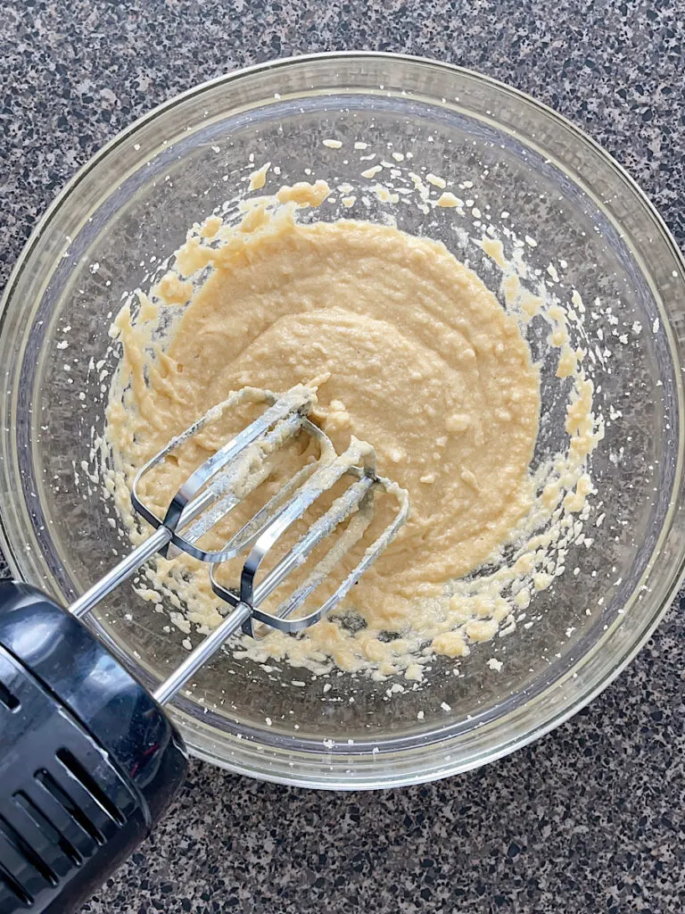 Cookie dough in a mixing bowl with an electric mixer.