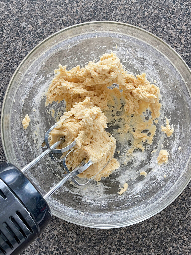 A bowl of cookie dough with an electric mixer.