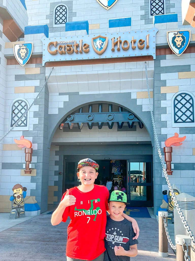 Two kids standing in front of the Legoland Castle Hotel.