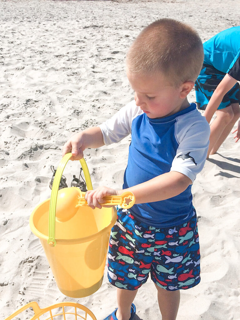 A child with a bucket of sand on the beach in San Diego.