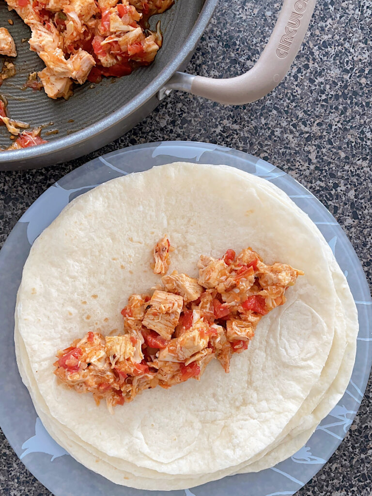 Chicken enchilada mixture in the center of a tortilla.