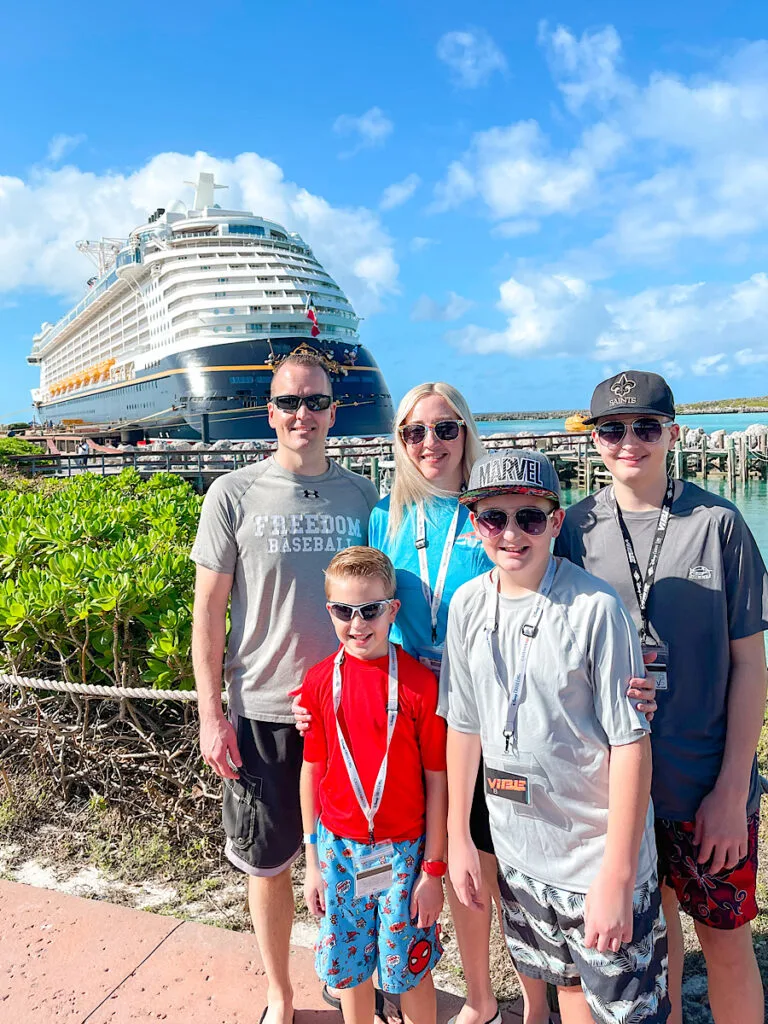 A family in front of the Disney Dream at Castaway Cay.