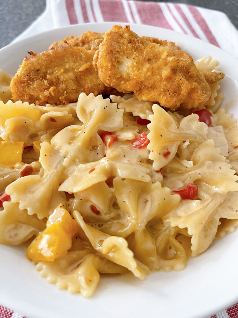 A bowl of Louisiana Chicken Pasta with chicken strips in a white bowl.