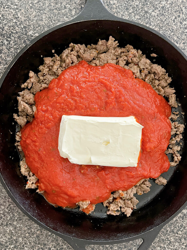 Ground sausage, marinara sauce, and cream cheese in a skillet.