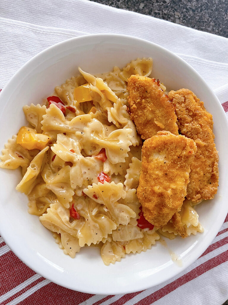 A bowl of Louisiana Chicken Pasta with chicken strips in a white bowl.