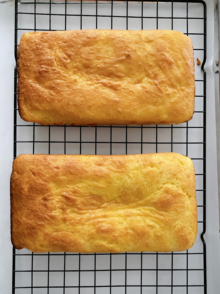 Two loaves of lemon bread on a cooling rack.