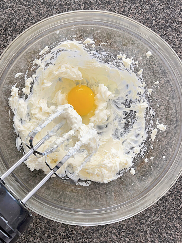 Cream cheese and an egg in a mixing bowl.
