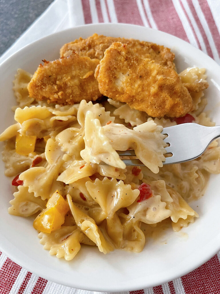 A bowl of Louisiana Chicken Pasta with chicken strips in a white bowl.