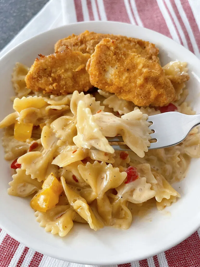 A bowl of Louisiana Chicken Pasta with chicken strips in a white bowl.