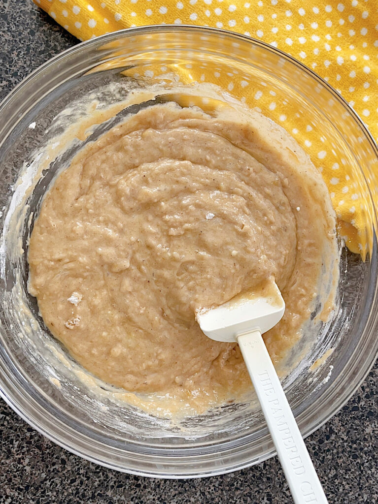 Cinnamon banana muffin batter in a bowl with a white spoon.