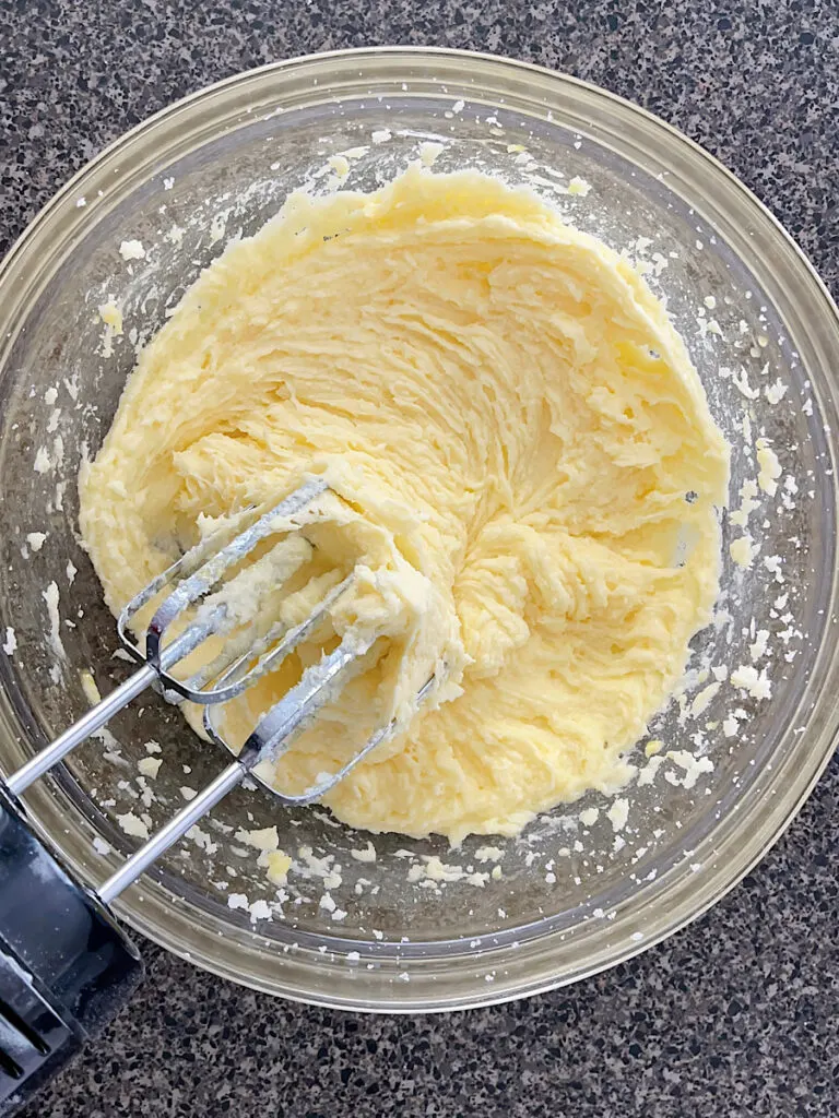 Butter, sugar, and eggs in a mixing bowl with an electric mixer.