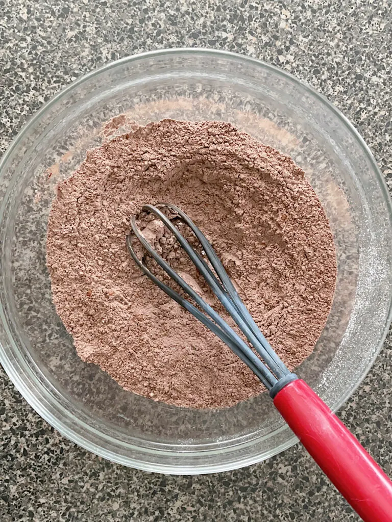 Dry ingredients for Reese's chocolate peanut butter chip cookies with a whisk.