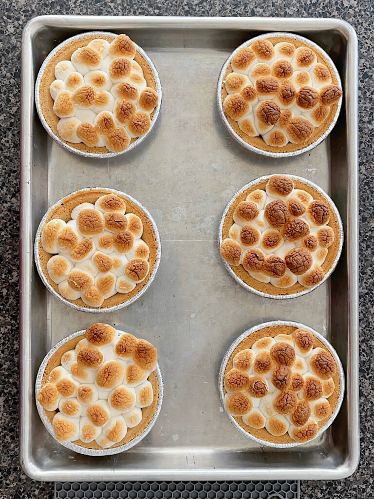 Mini marshmallows and chocolate inside mini graham cracker pie crusts.