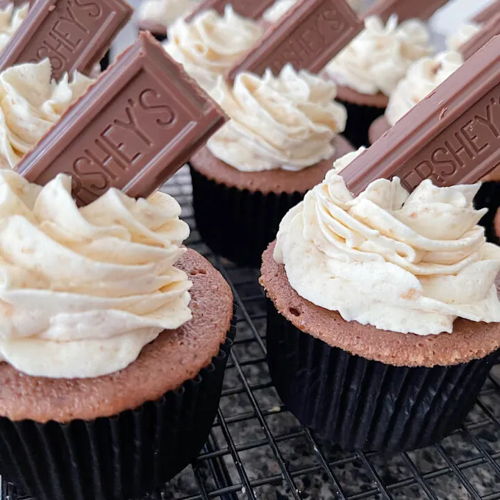 Chocolate cupcakes with graham cracker frosting and a piece of a Hershey's chocolate bar on top.