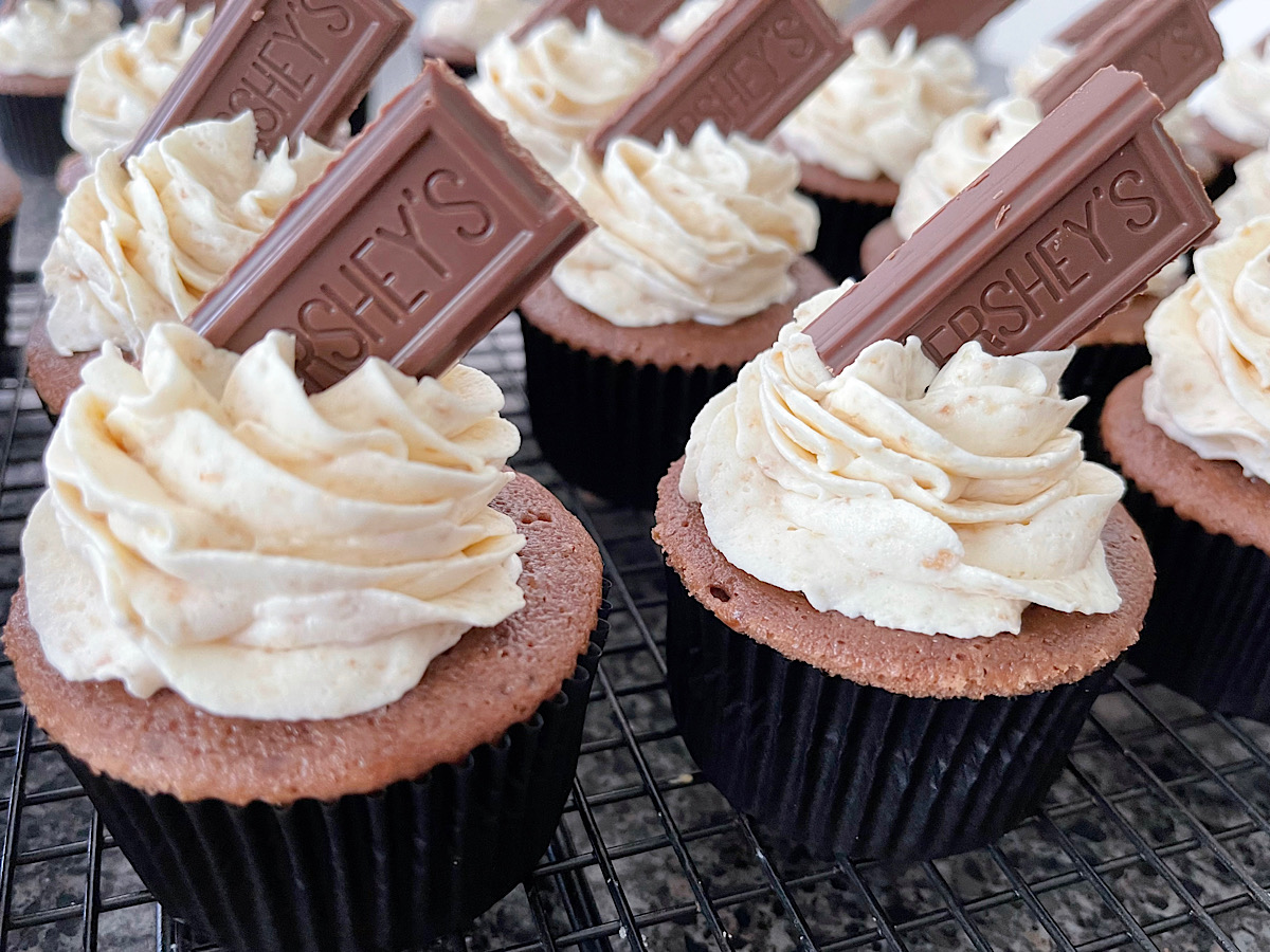 Chocolate cupcakes with graham cracker frosting and a piece of a Hershey's chocolate bar on top.
