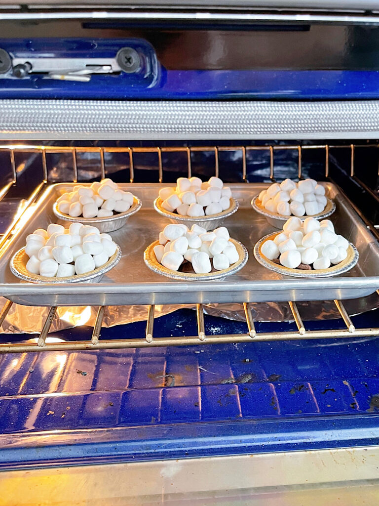 Mini s'mores pies baking in an oven.