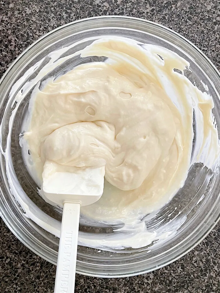 Whipped cream and cream cheese in a mixing bowl.