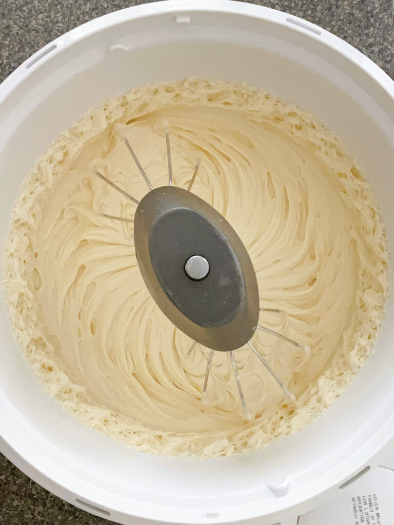 White cake batter in the bowl of a stand mixer.
