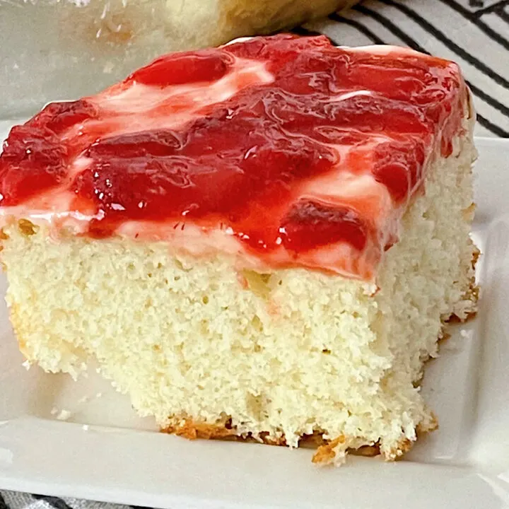 A slice of strawberry cream cake on a white plate.