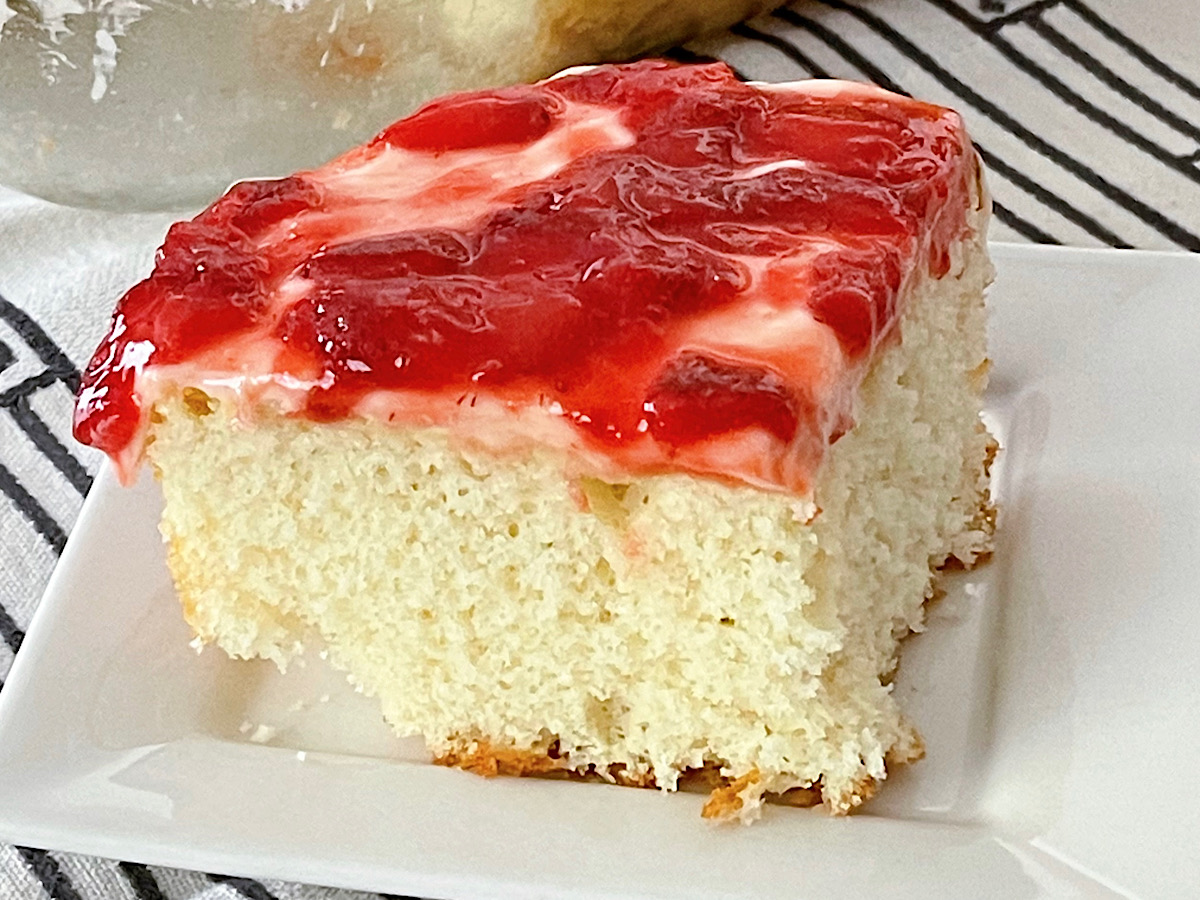 A slice of strawberry cream cake on a white plate.