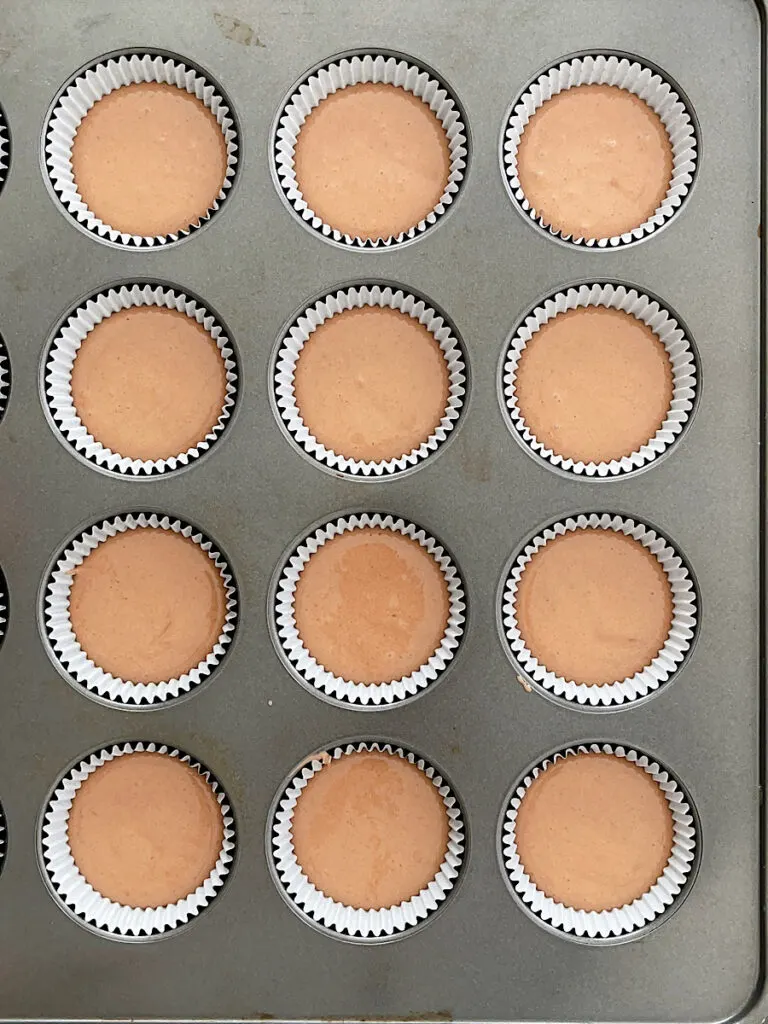 Cupcake batter in cupcake liners in a pan.