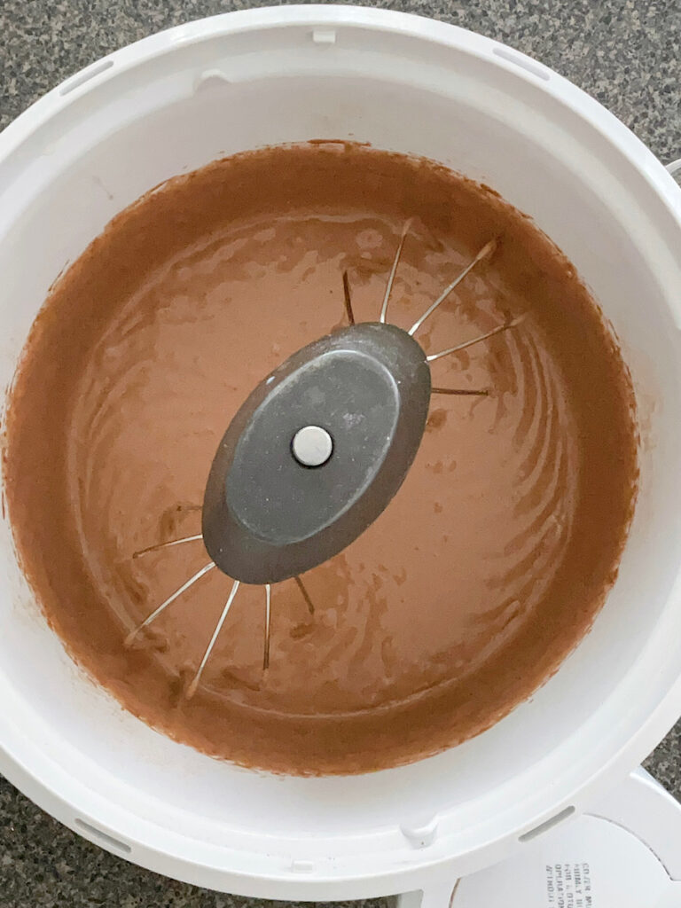 Chocolate cupcake batter in a stand mixer with a whisk attachment.