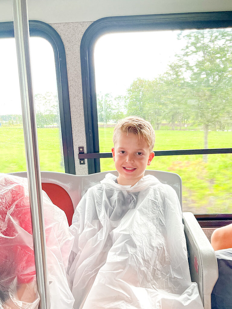 A child in a poncho on a Disney World bus.