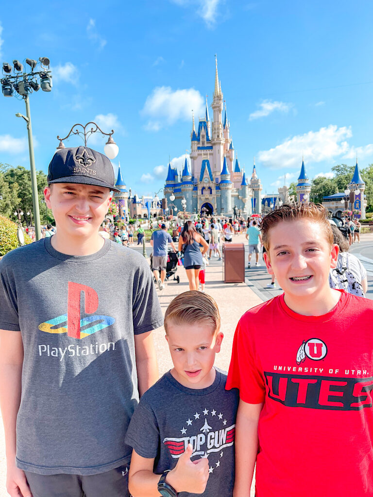 Three boys in front of Cinderella's Castle at Disney World.