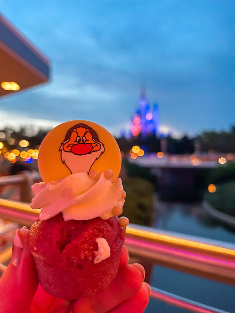 A cupcake with Grumpy on top in front of Cinderella Castle at Magic Kingdom.