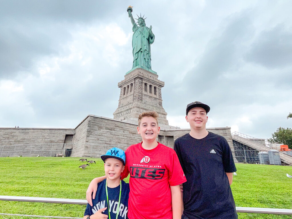Three kids in front of the Statue of Liberty.