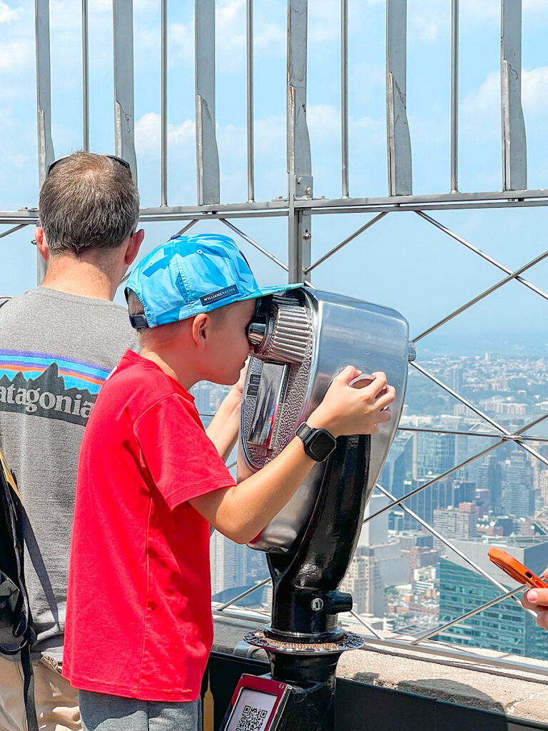 A child looking in a view finder on top of the Empire State Building.