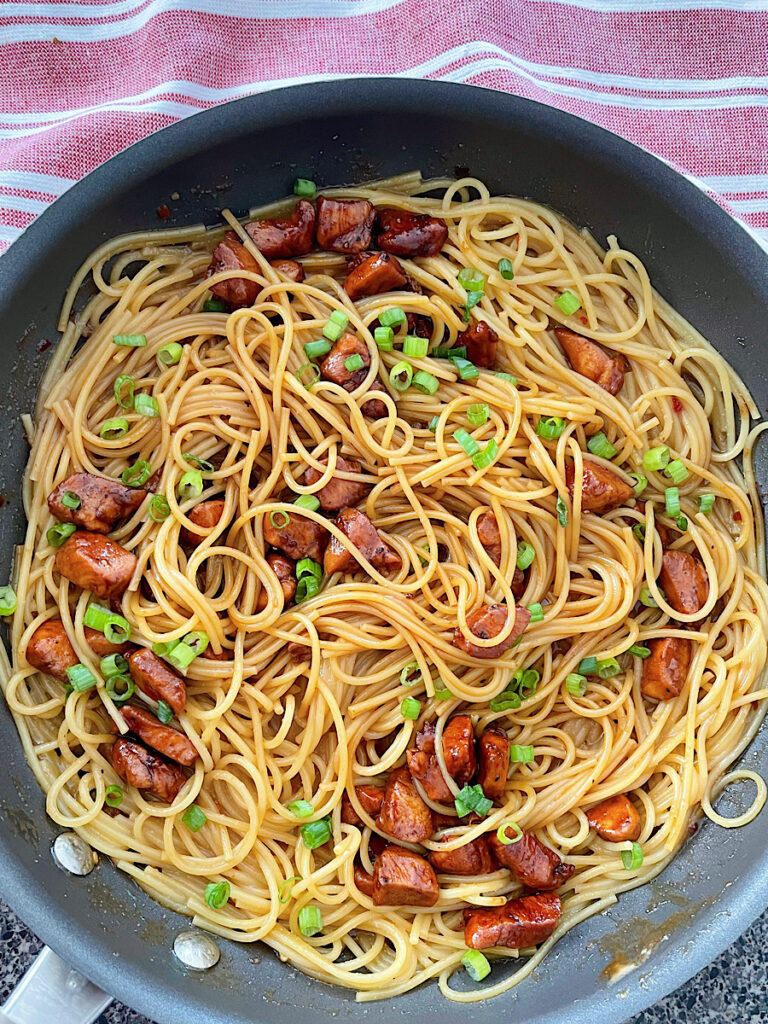 Spicy Thai noodles with chicken in a large skillet.