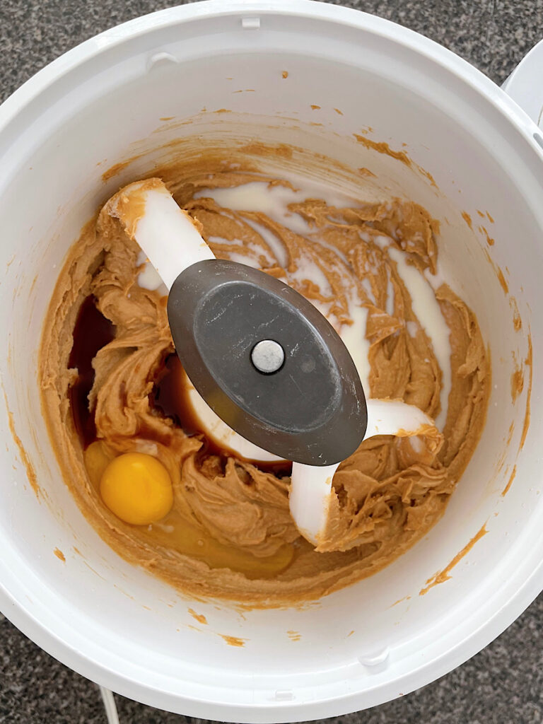 Egg, milk, and vanilla added to a bowl of peanut butter, butter, sugar, and brown sugar.