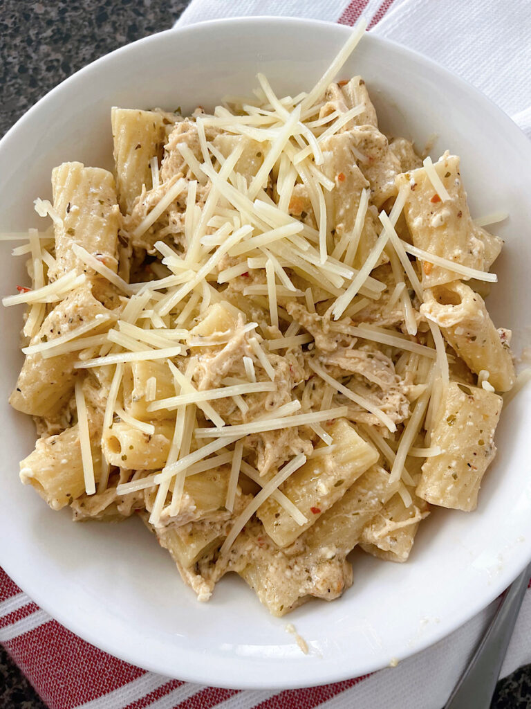 A bowl of Buffalo Wild Wings Garlic Parmesan Chicken Pasta topped with shredded parmesan cheese.