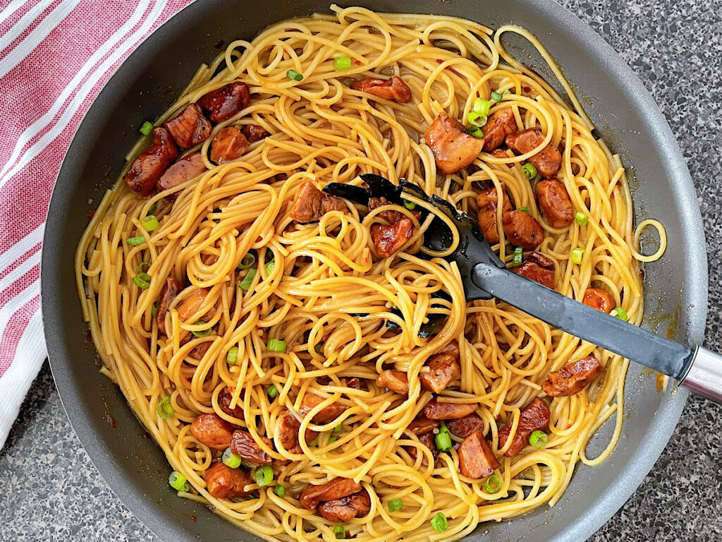 Spicy Thai noodles with chicken in a large skillet.