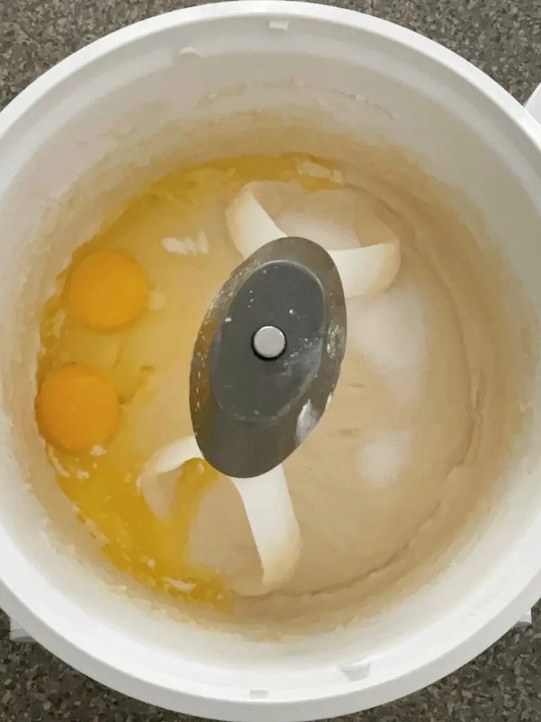 Eggs and cheesecake batter in the bowl of a stand mixer.